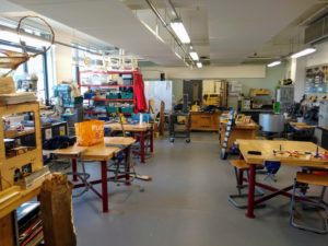 A wide photo of the room, with workbenches and tools
